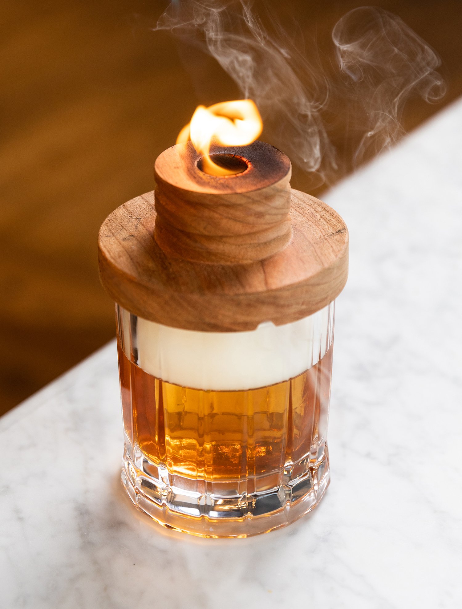 A wooden candle featuring a vibrant flame