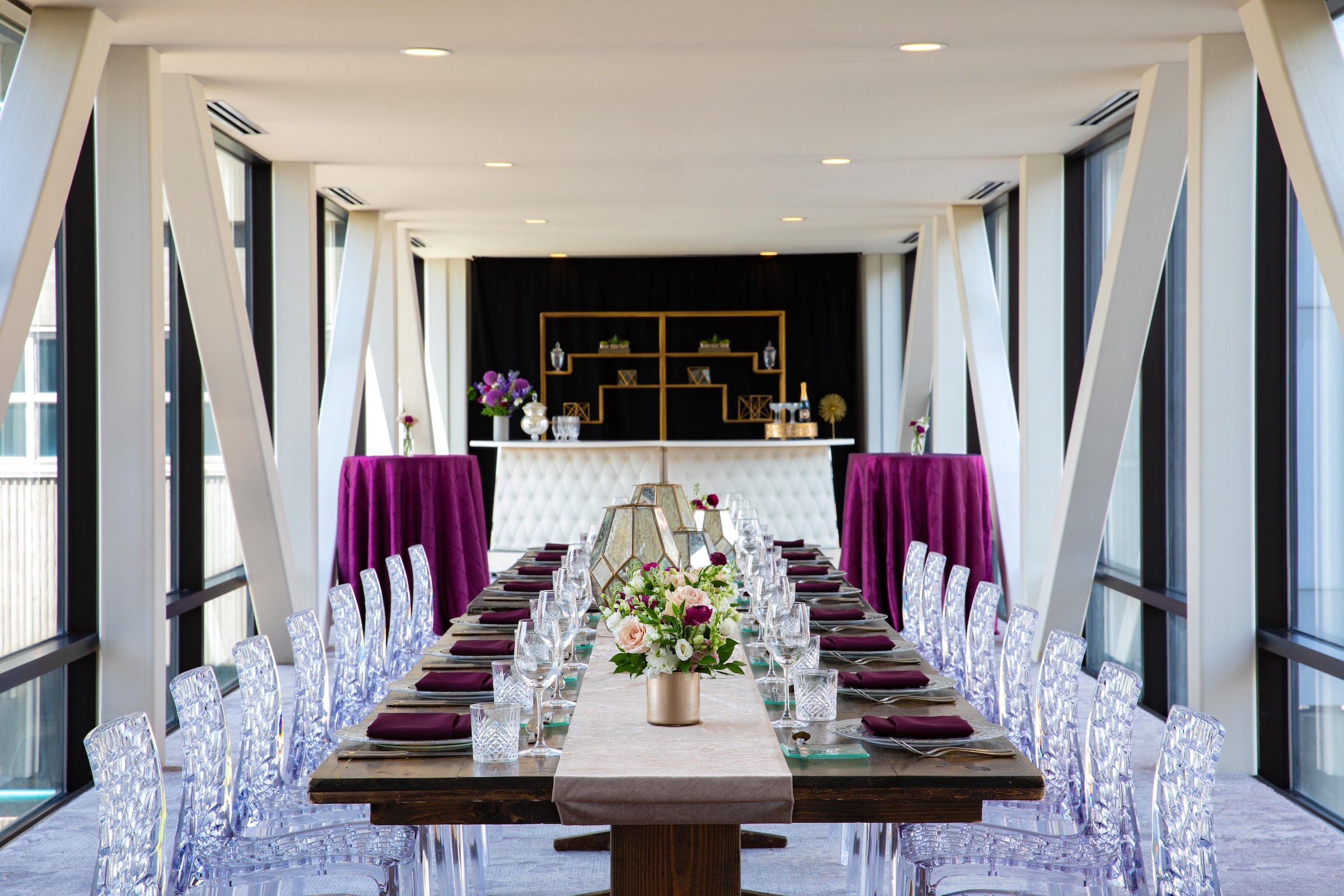 A dining settings in a bright space with large glass windows , Skyway venue at Hotel Ivy