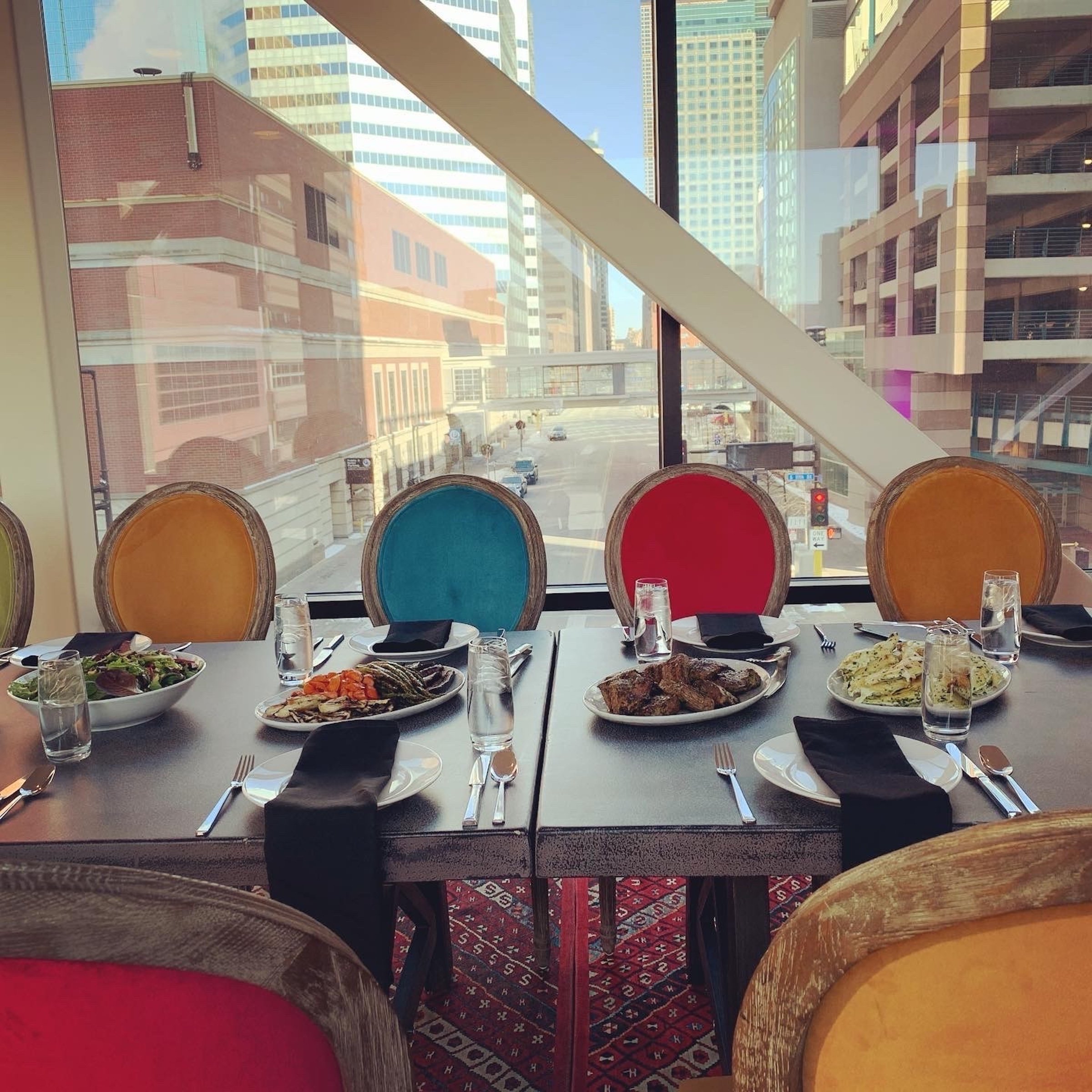 Colourful lunch event settings behind solid glass showing buildings and a parking lot