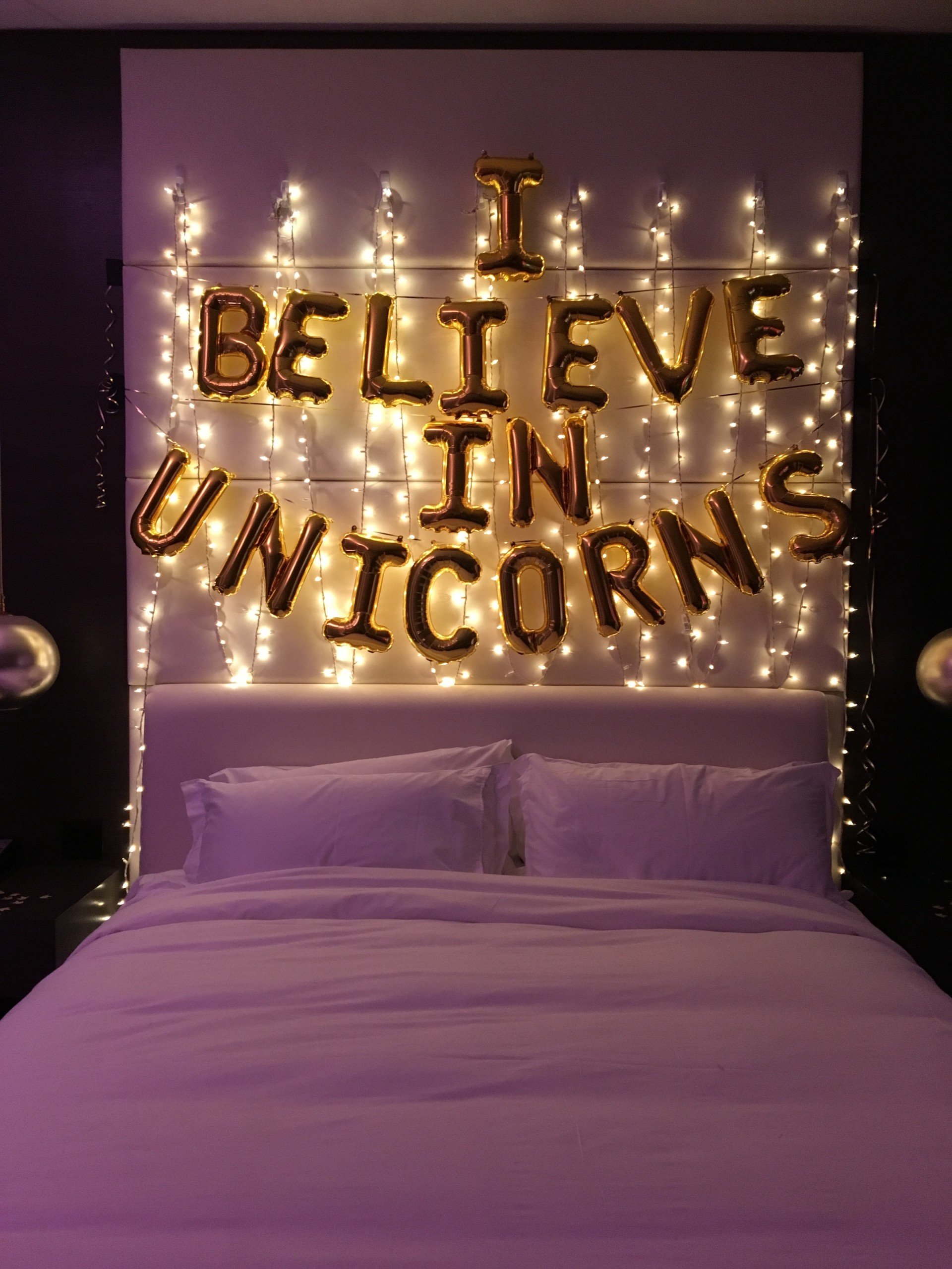 Golden balloons saying 'I believe in Unicorns' with lights on the wall in the bedroom of Penthouse Suites at Hotel Ivy