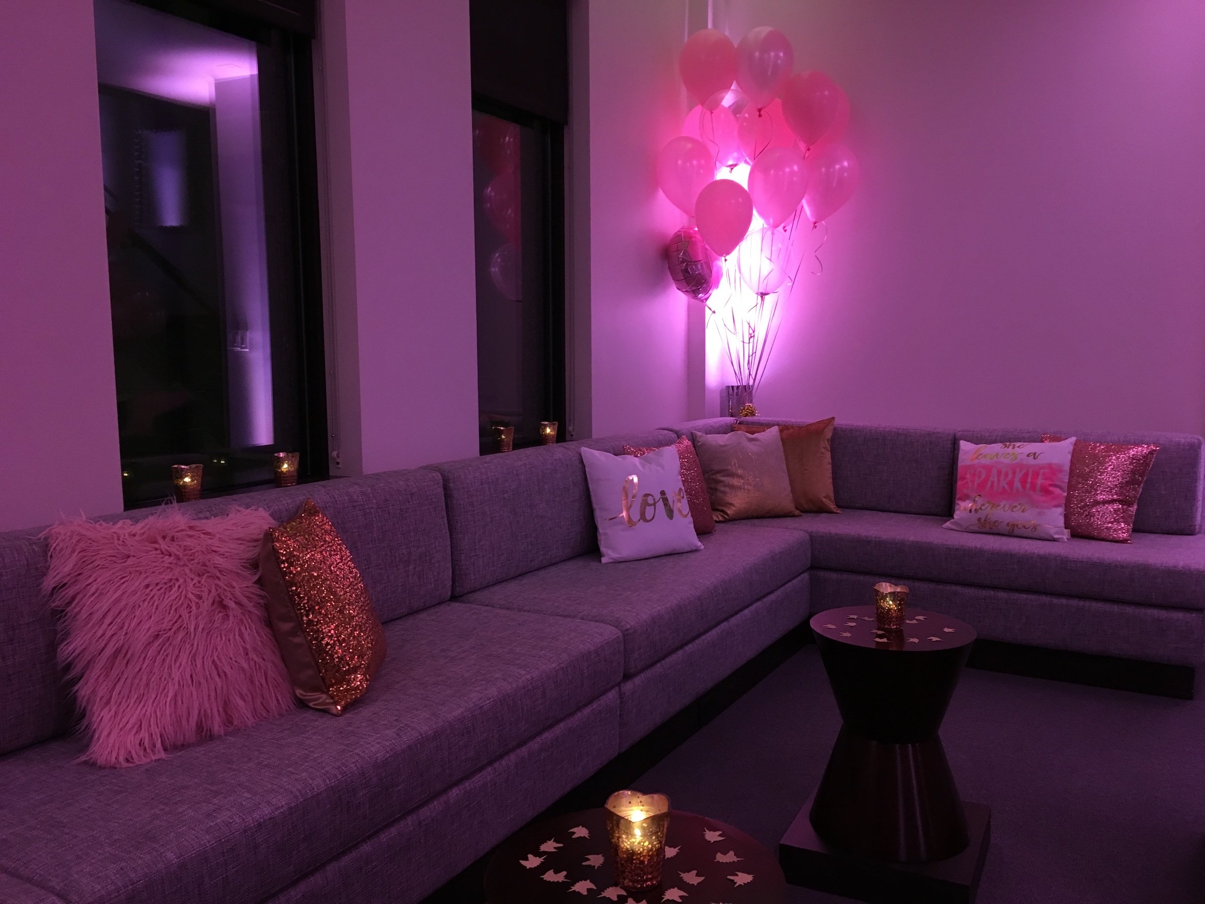 a grey L-shaped couch with unique cushions with helium balloons with pink lightings from the lounge area of Penthouse Suites at Hotel Ivy