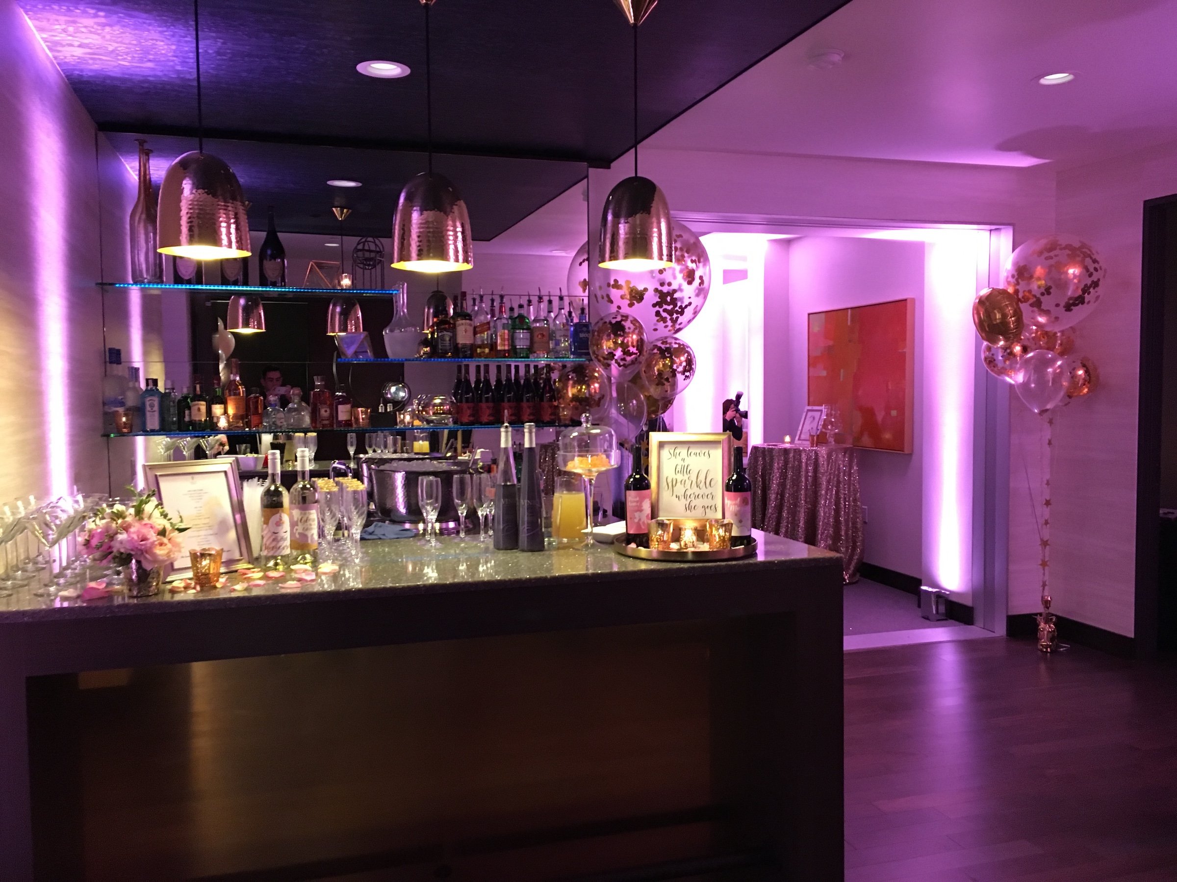 A stylish event set up with modern bar illuminated by warm golden and pink lighting at Penthouse Suite of Hotel Ivy