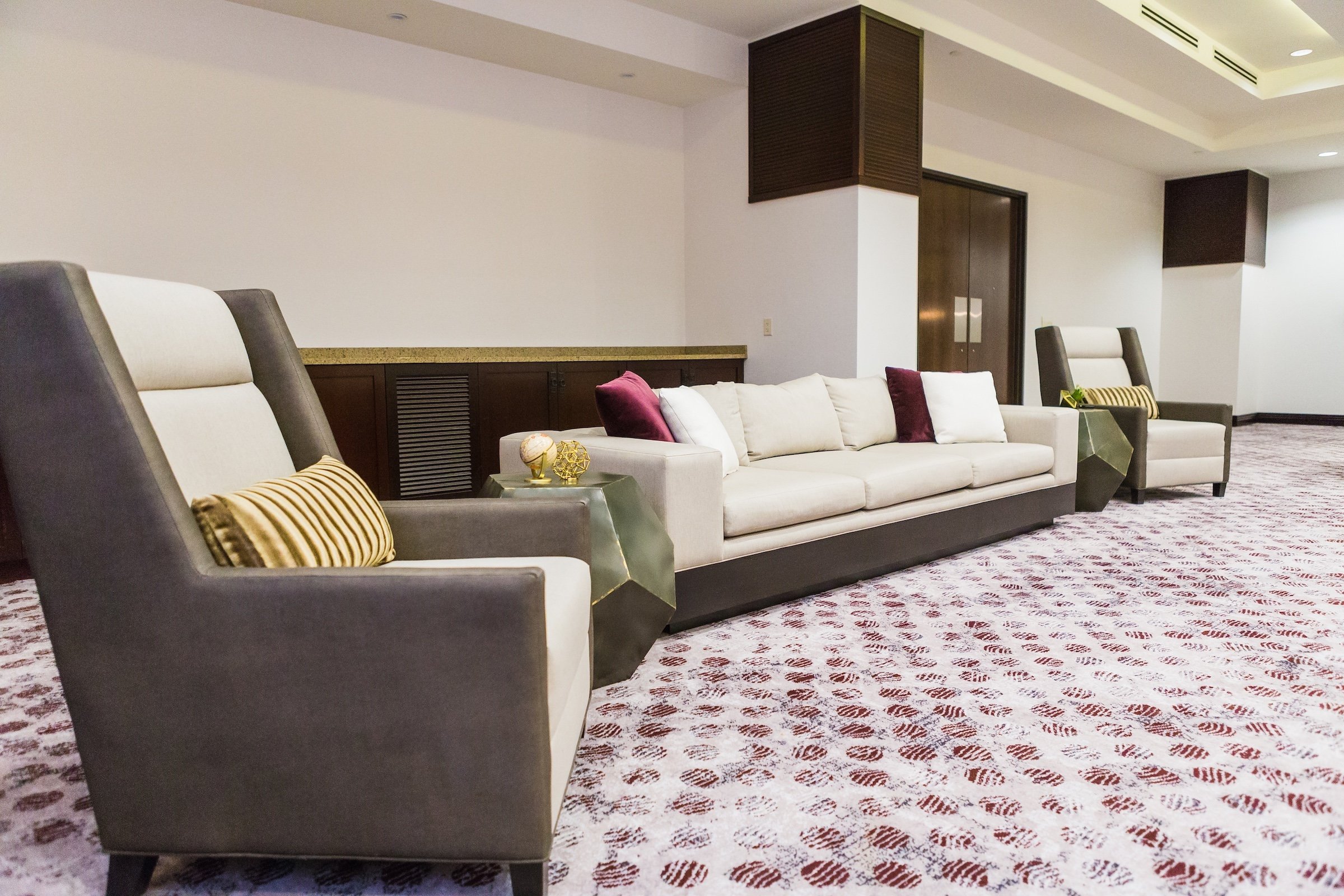 grey and white toned couches with burgundy, white and golden cushions in the white modern venue, Pre-function Space at Hotel Ivy