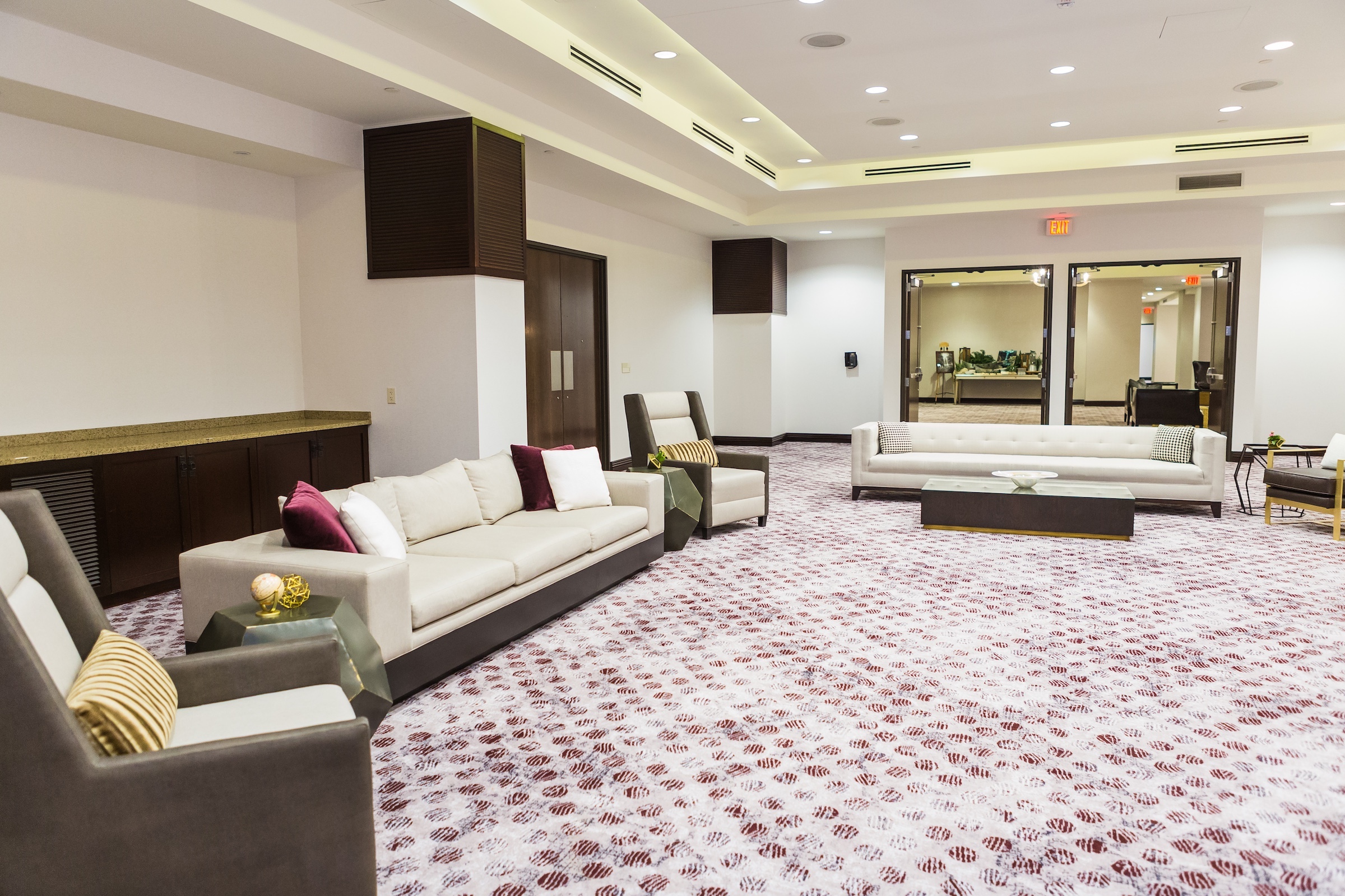 Couches, chairs, tea table, etc. in a large meeting space with two door entrances at Pre-function Space, Hotel Ivy