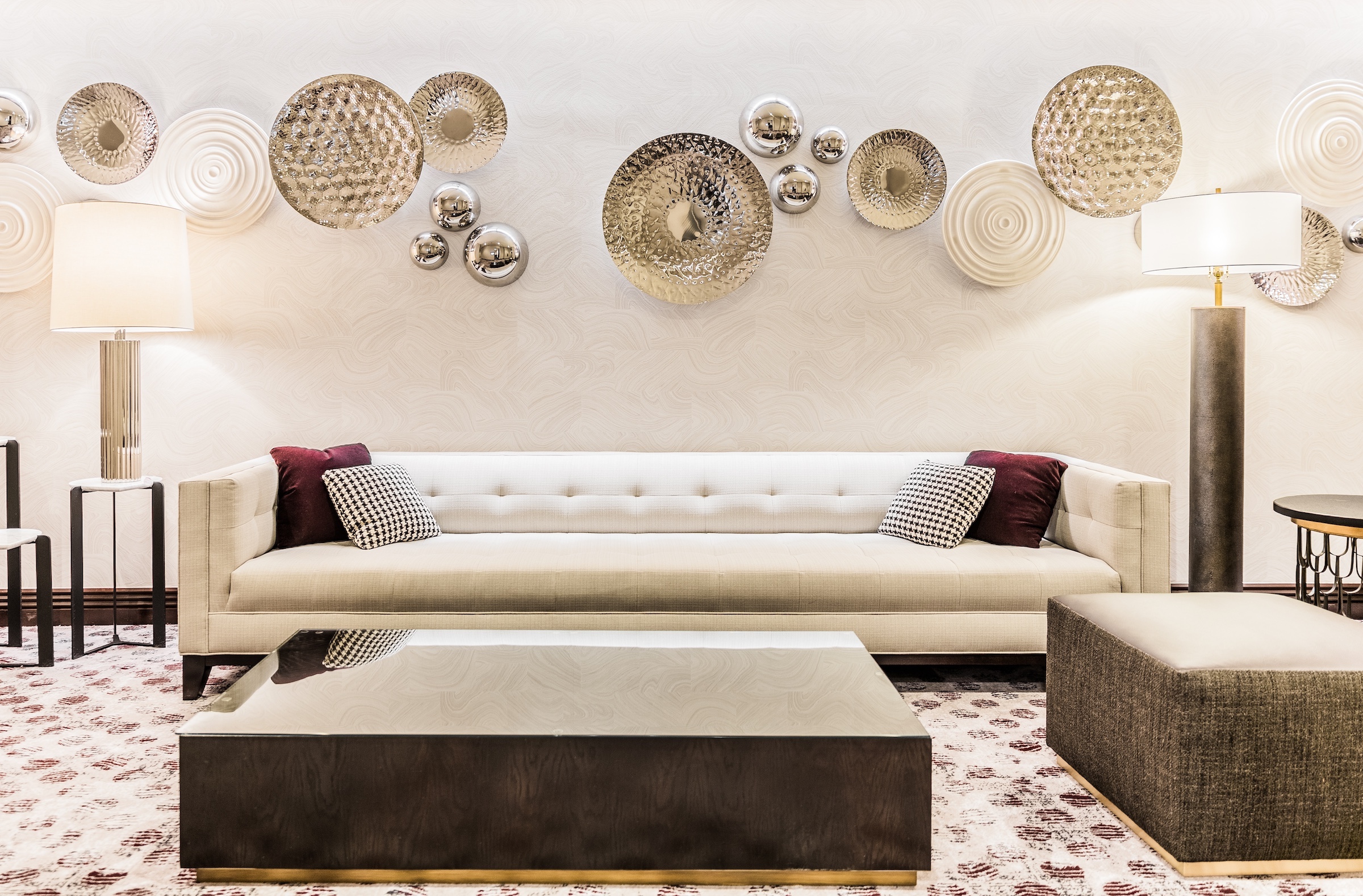 Circular decorations with various materials on a wall with a white couch, dark marble tea table, etc. in a white classic modern space, Pre-function space at Hotel Ivy