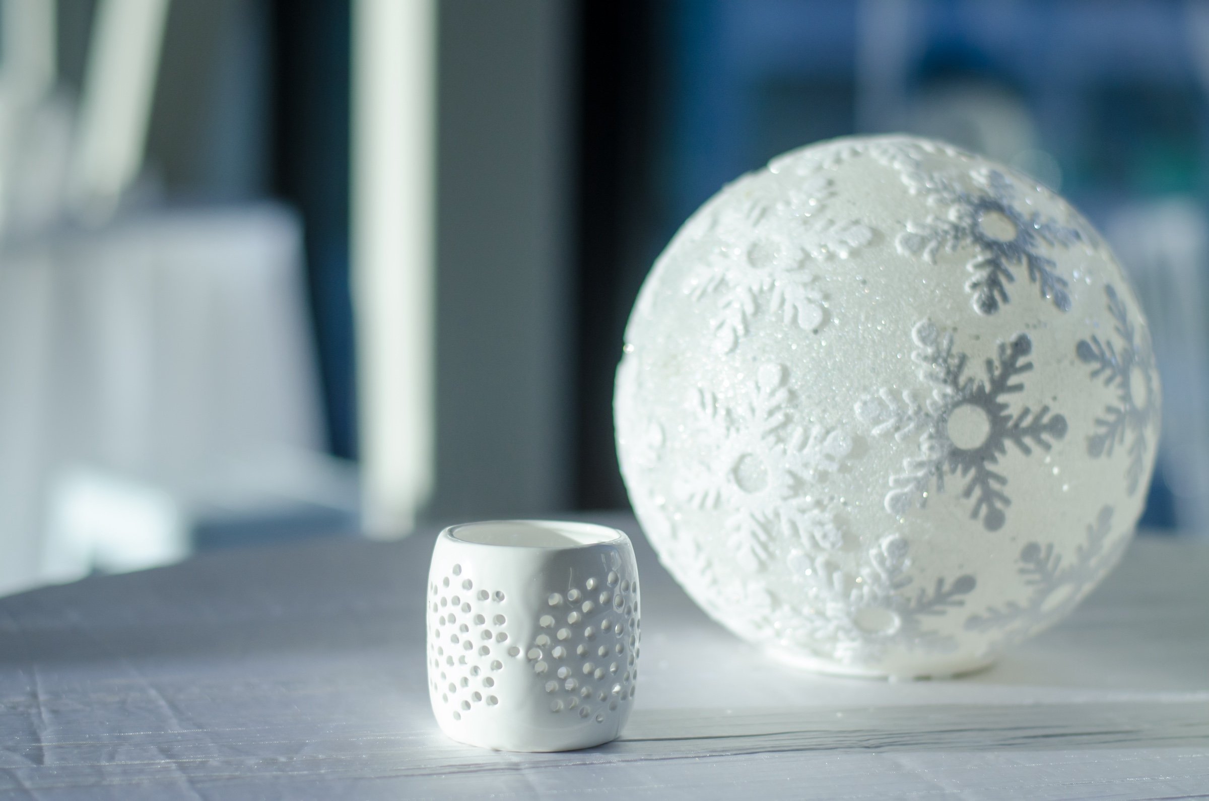 A sophisticated white decorations of a snowflake carved ball and a candle cup from Skyway at Hotel Ivy