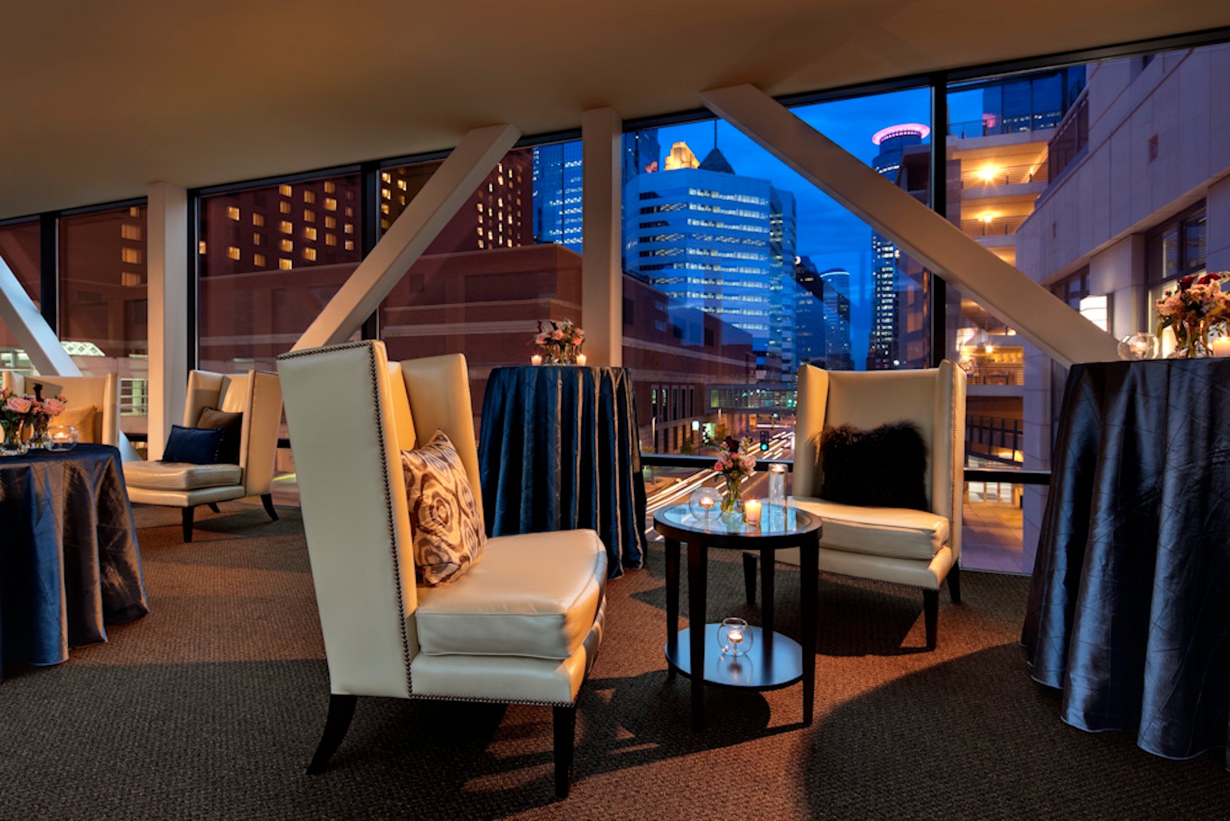 Comfortable ivory chairs and high tables with silk black cloth in Skyway venue from Hotel Ivy in the evening