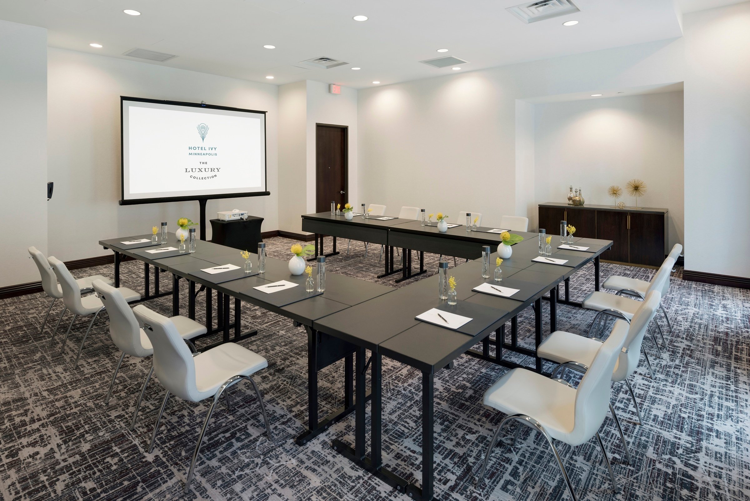 A U-shaped of desks with chairs in a bright venue, Exhibit at Hotel Ivy