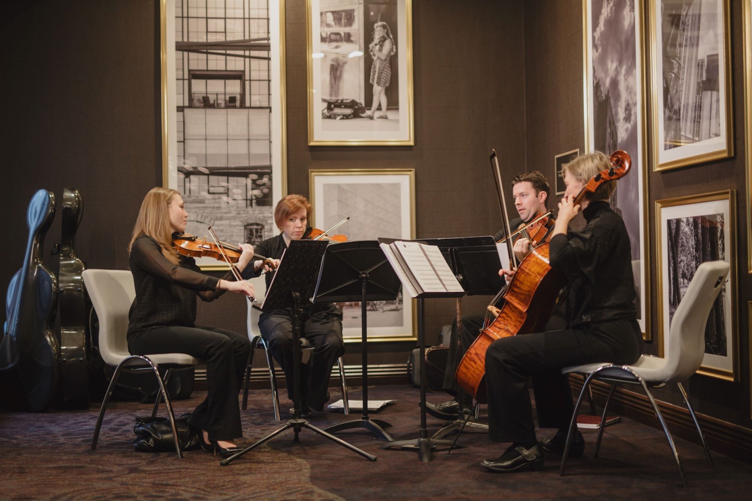 String Quartet playing next to golden frames of black and white photography in a modern venue for Caroline and Mike's wedding at Hotel Ivy