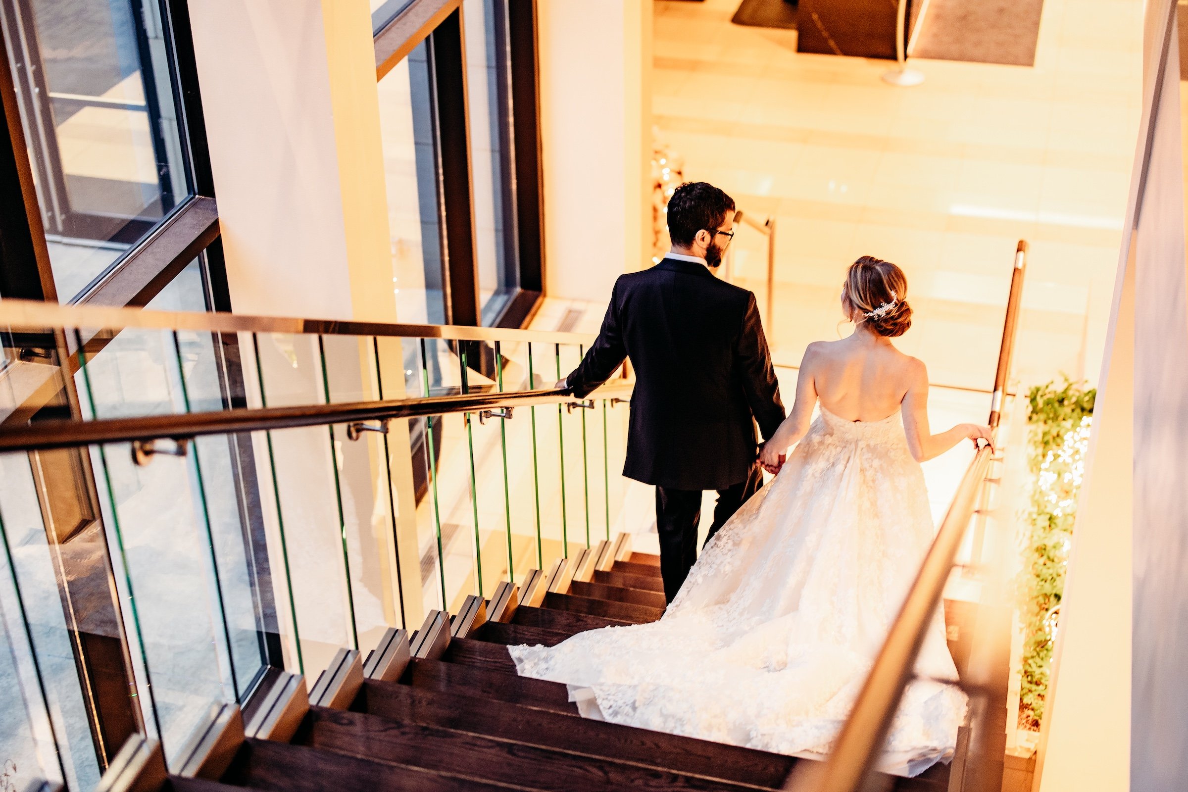 Granby & Sprung's wedding - A couple walking down stairs next to large windows at Hotel Ivy