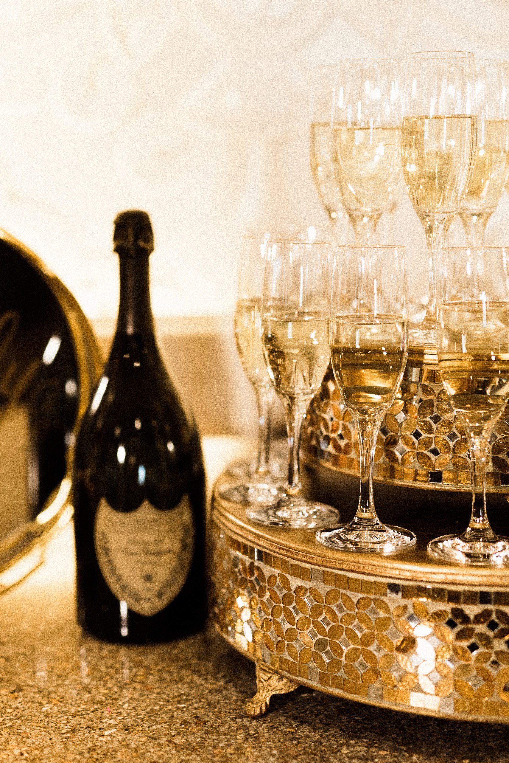 A table setting of glasses filled with champagne and champagne bottle on golden plates and table in warm atmosphere at Hotel Ivy