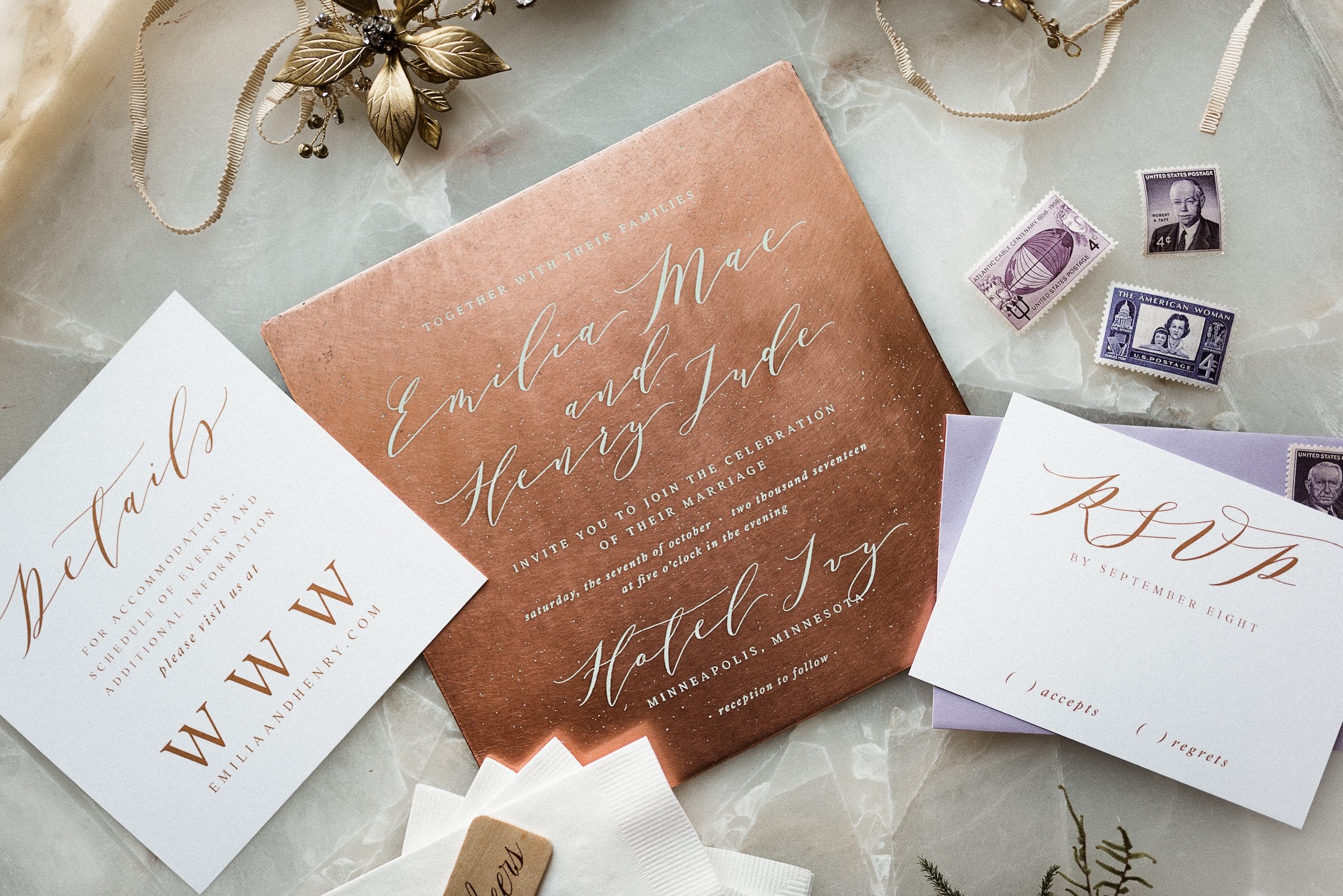 Stylish invitation cards with details and stamps on a white marble table