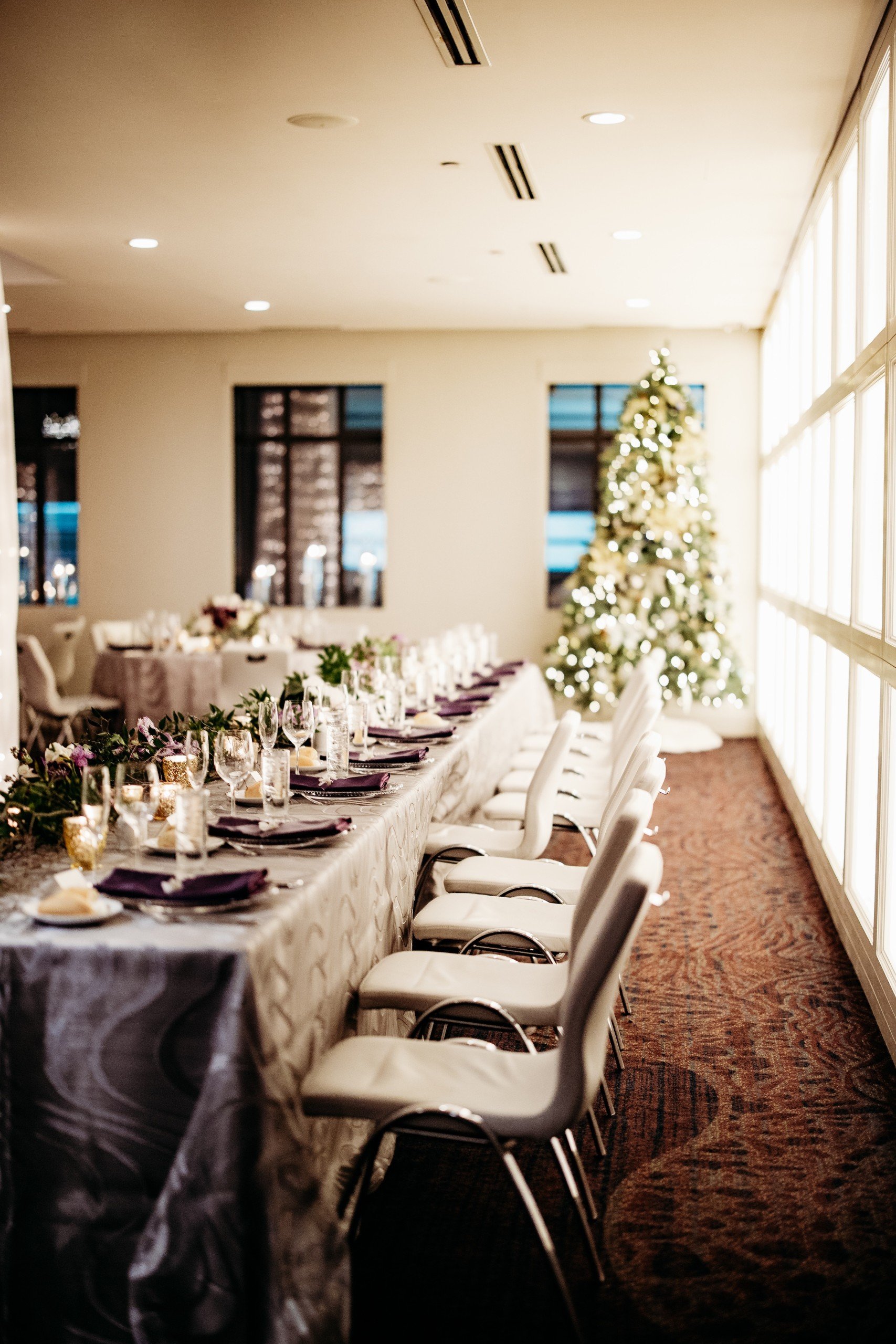 An event settings with lighting Christmas tree next to an elegant windows in a bright space for Granby and Sprung's wedding