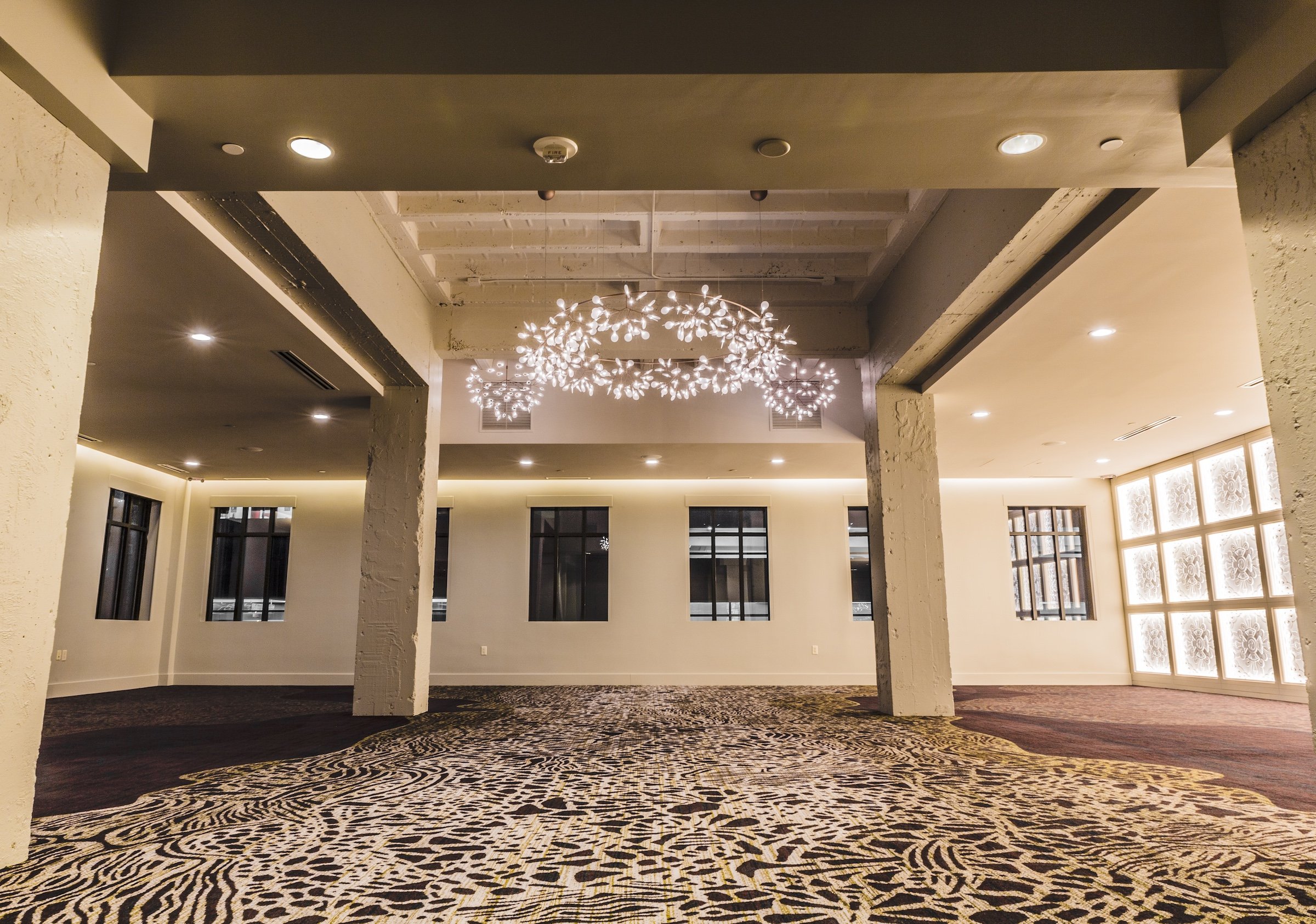 A stylish event space in Hotel Ivy’s Grand Studio, highlighted by elegant chandeliers resembling branches with glowing bulbs, and a sophisticated modern aesthetic.