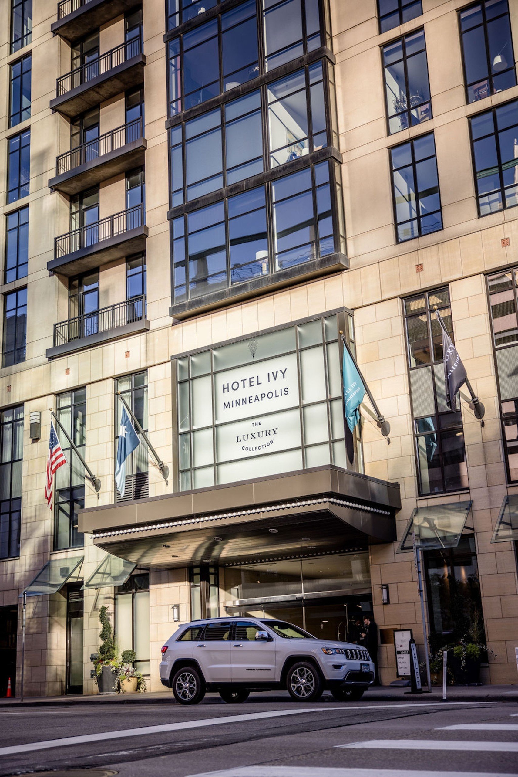 A large white SUV car in front of the entrance of Hotel Ivy