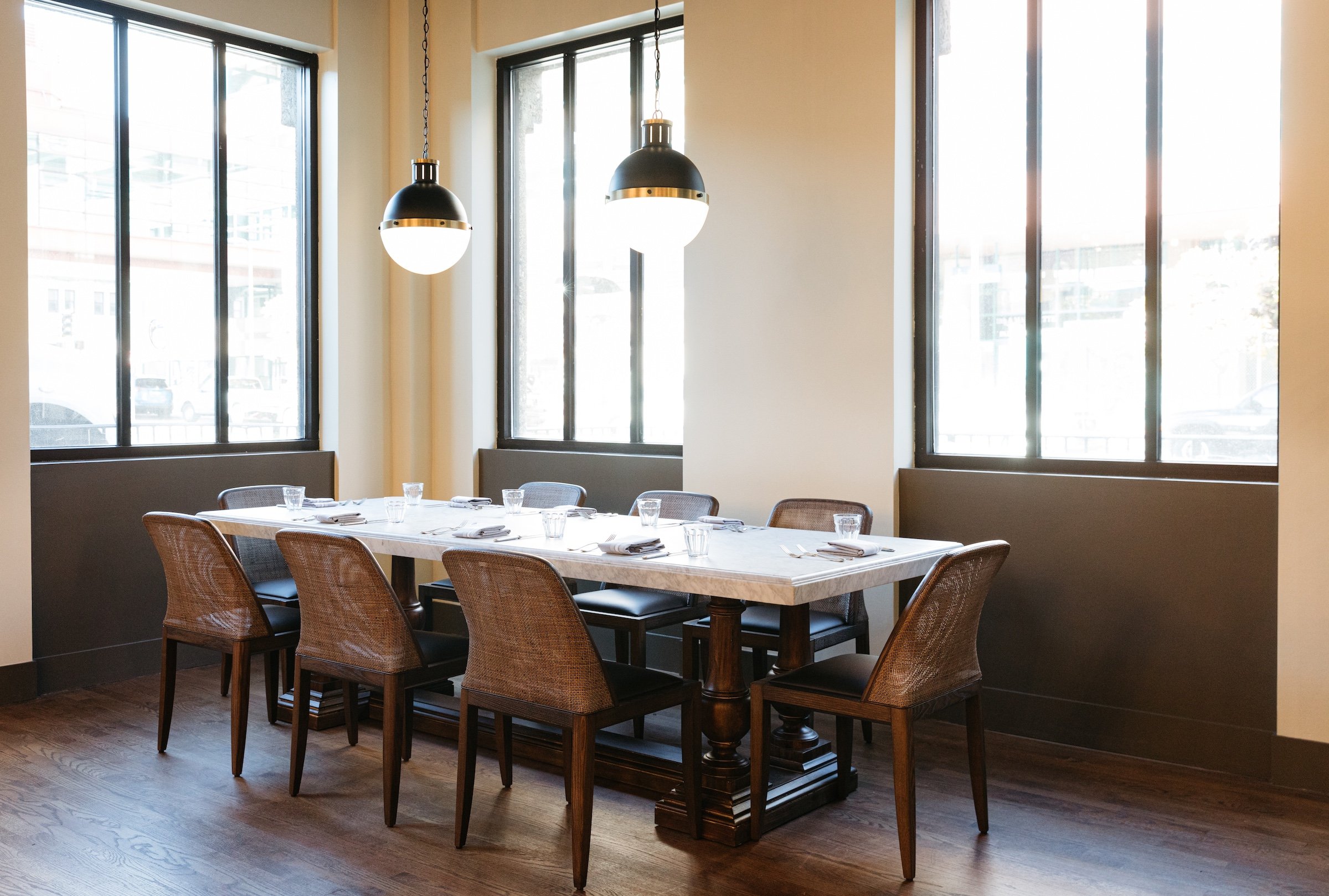 a group table near the large windows under round lighting bulbs at Breva