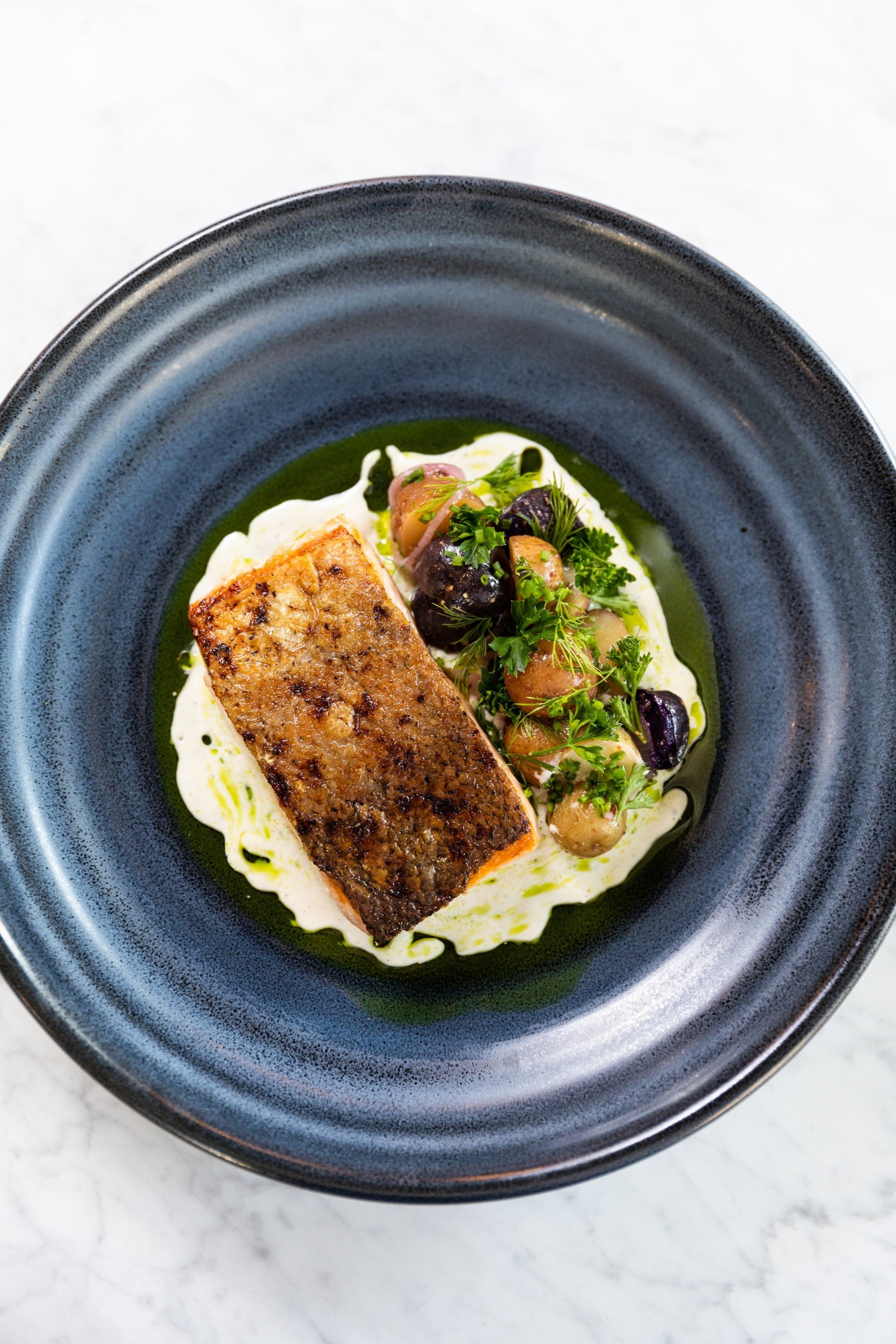 Salmon Bravas in a navy ceramic bowl on a white marble table