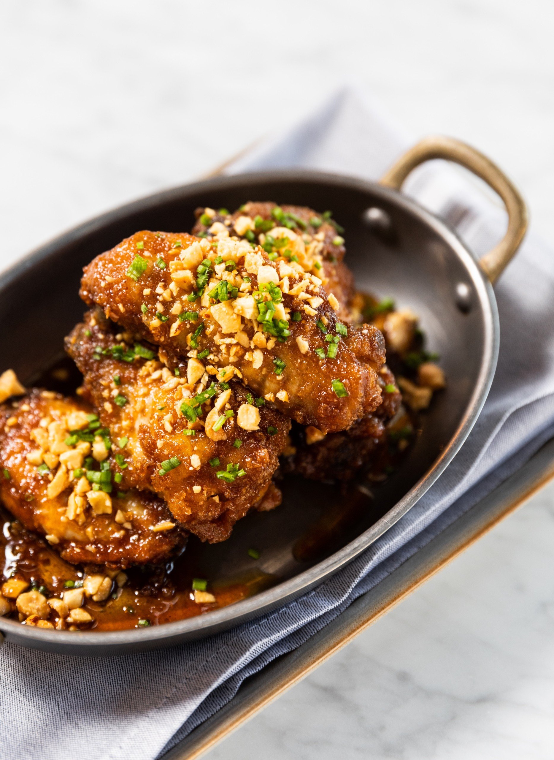 A close shot of Honey Chicken wings on a white marble table at Breva, Hotel Ivy