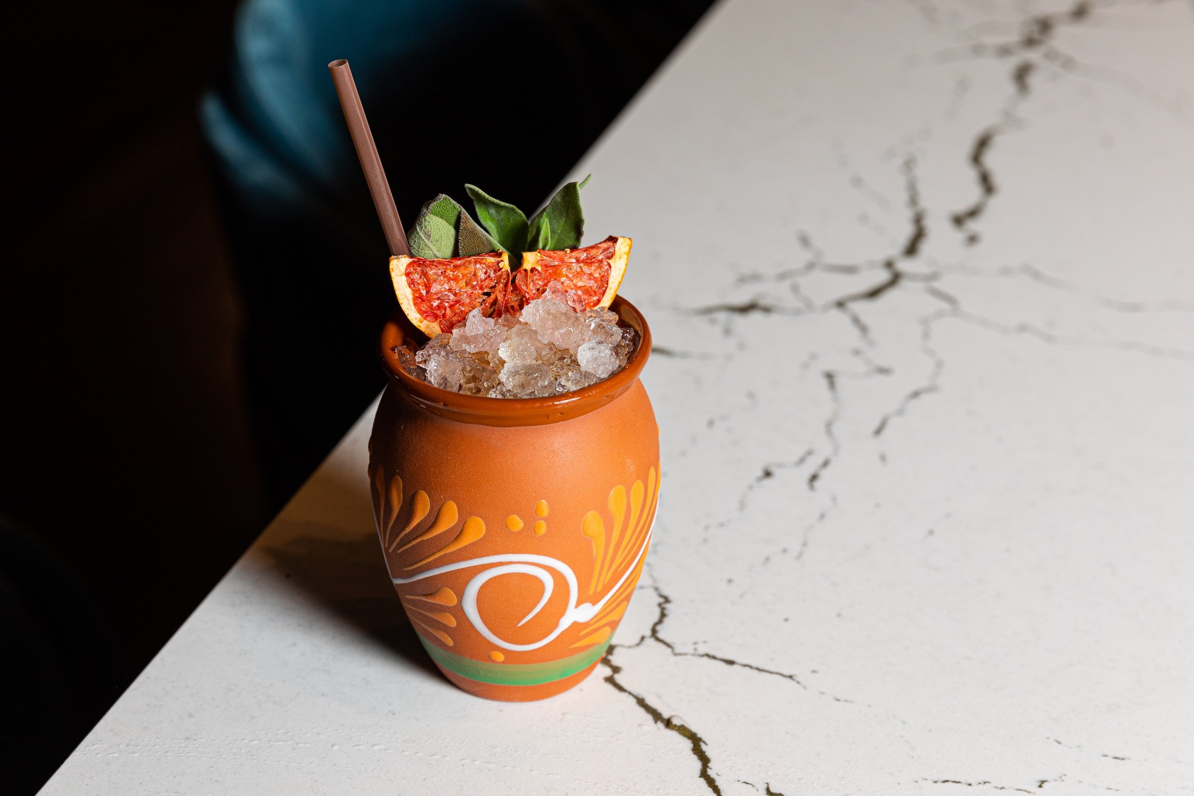 Mexican firing squad in a orange round cub with grapefruit on top from white marble table at Masa & Agave from Hotel Ivy