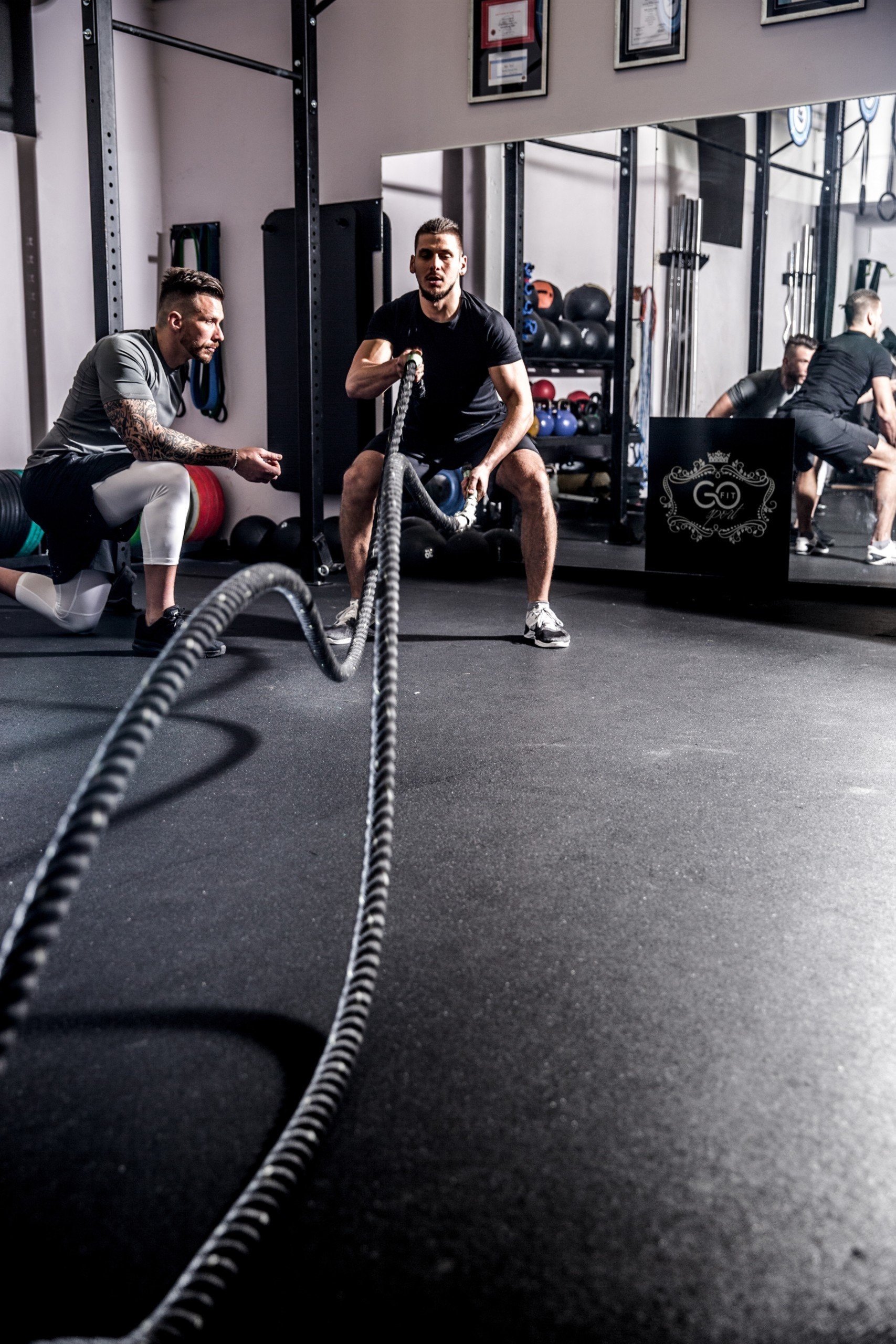 a men doing rope exercise with his personal trainer