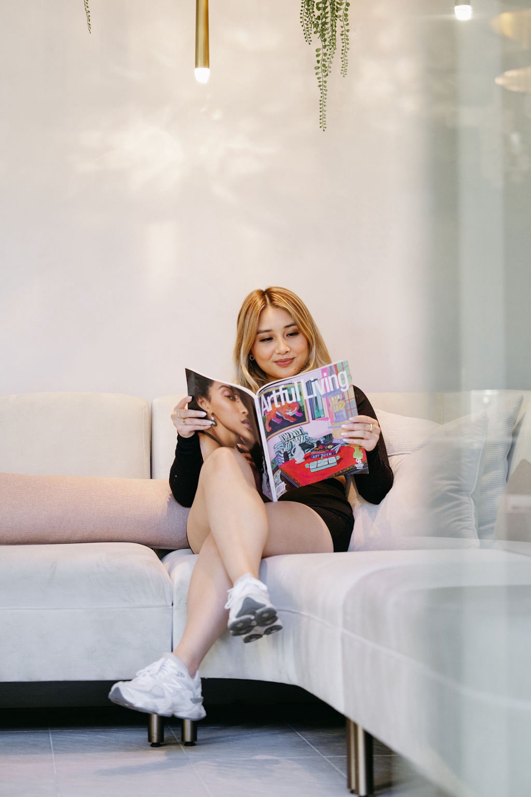 A woman reading a magazine called 'Artful living' on a white couch at Lobby of Anda Spa from Hotel Ivy