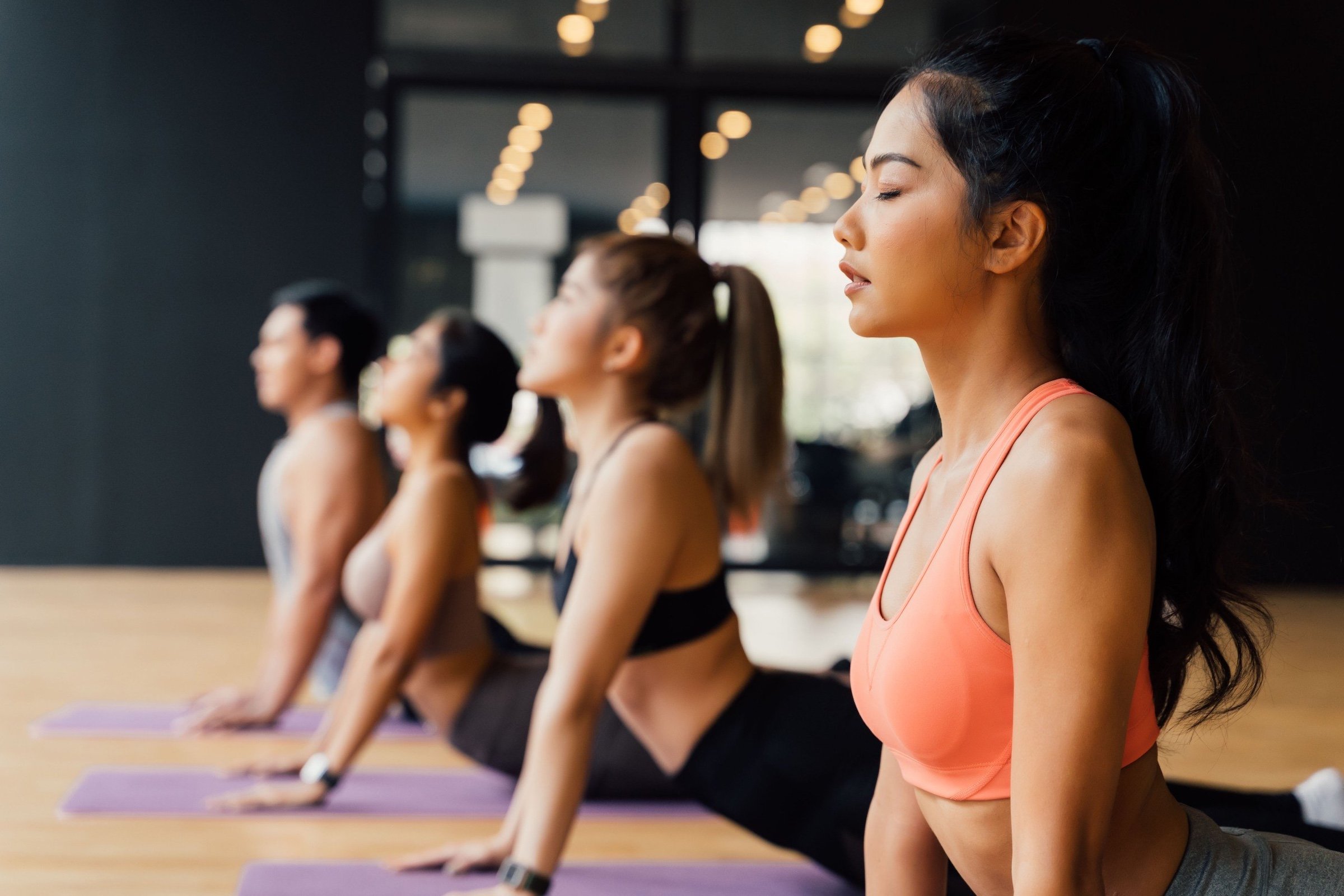 Three women and one man participating their yoga classes on their yoga mat