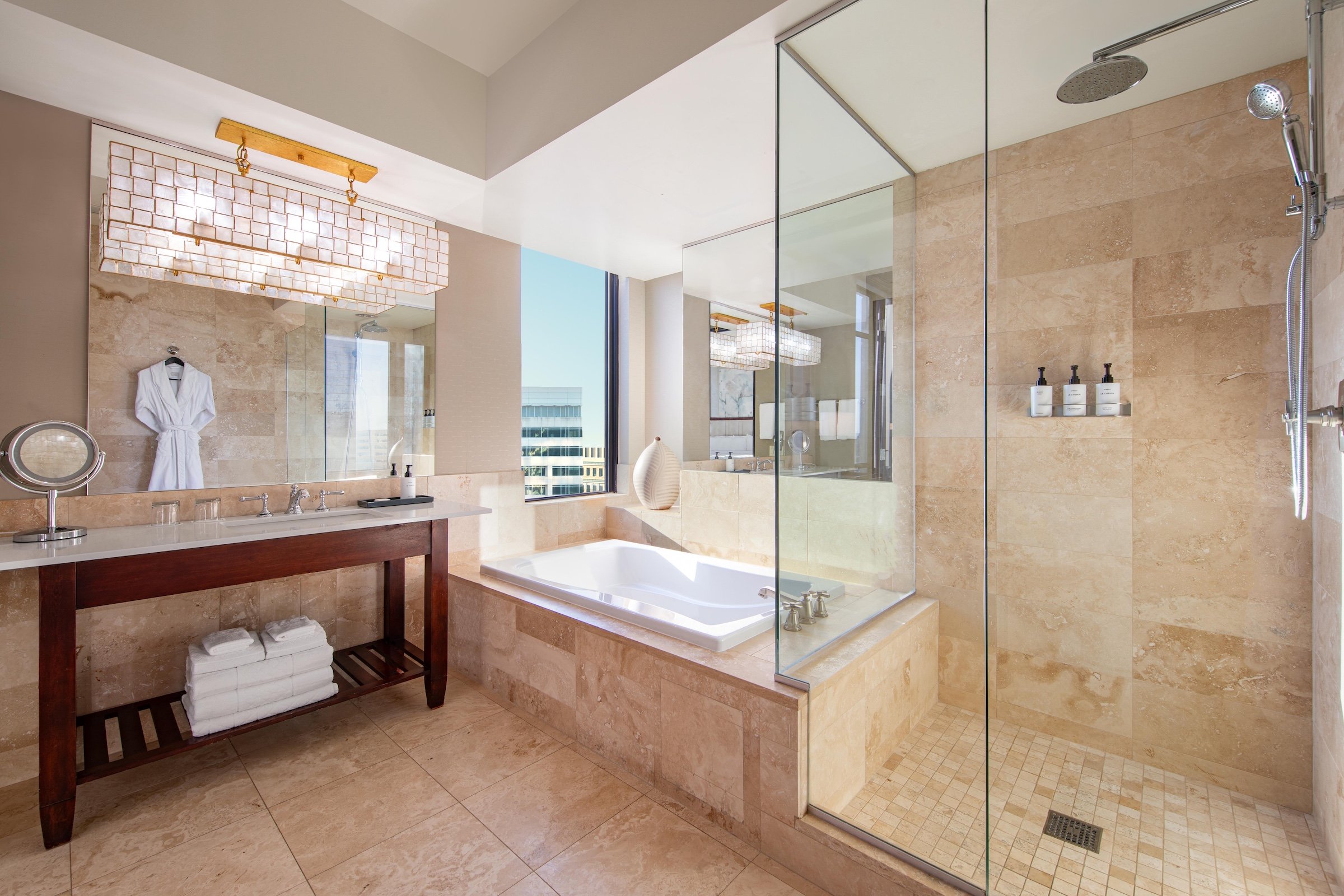 A large bright bathroom with a rainfall shower booth, a white bathtub and a sink at Hotel Ivy