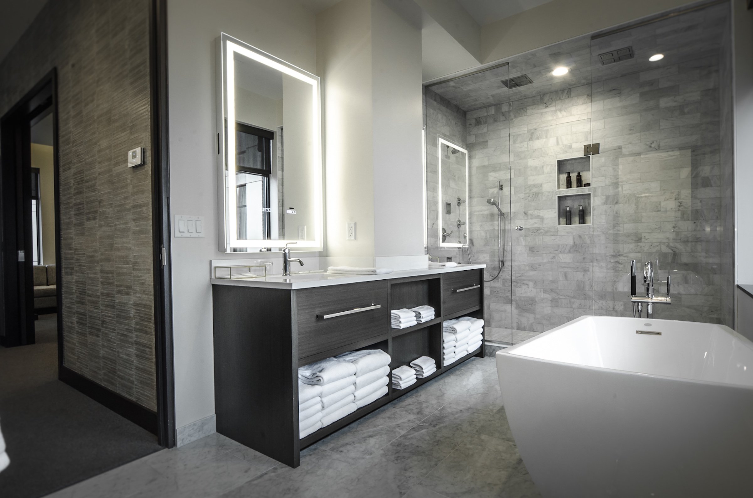 A sink filled with towels and amenities, shower booth, and a white bath tub at Penthouse Suite of Hotel Ivy