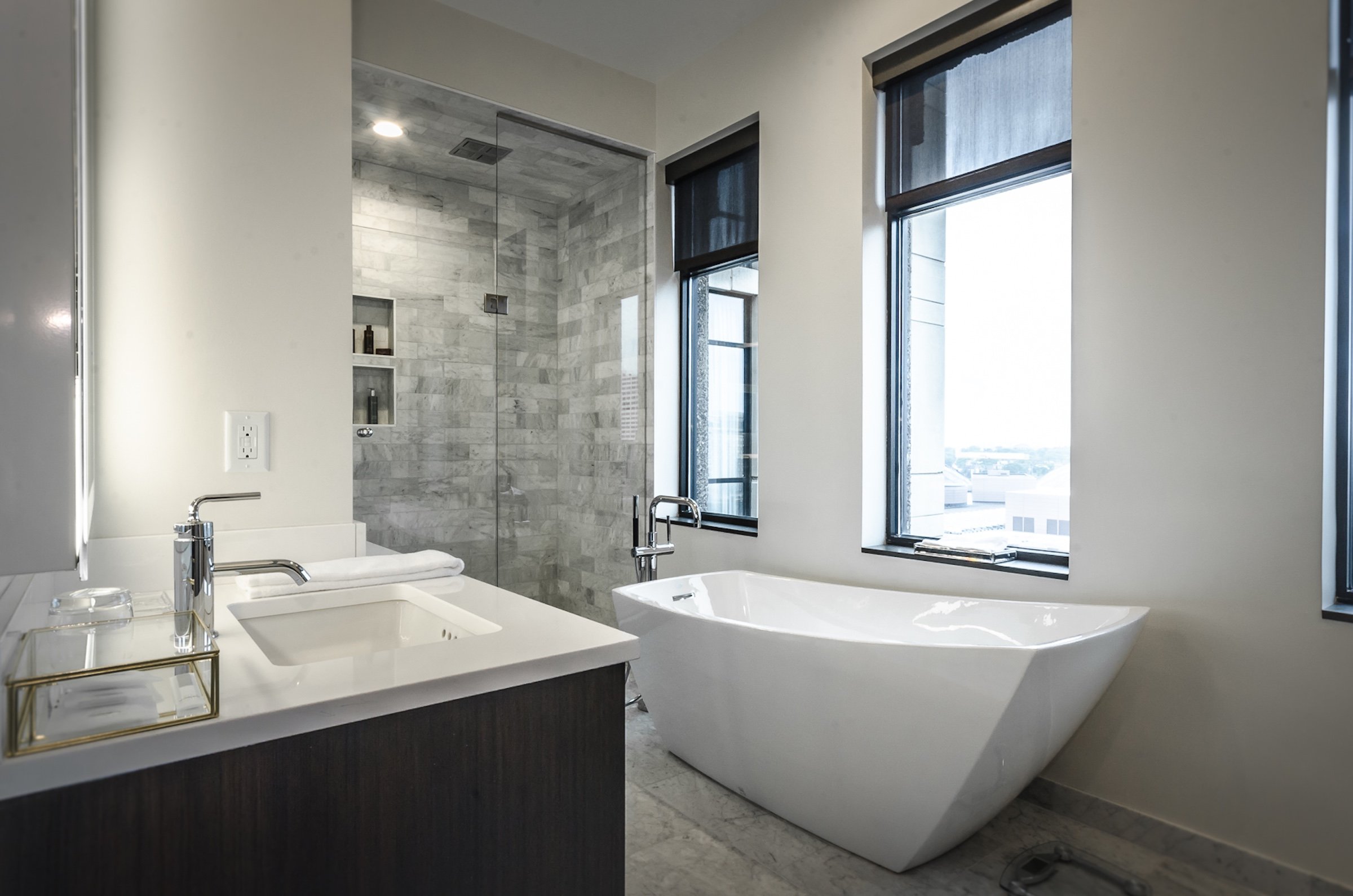 A sink filled with towels and amenities, shower booth, and a white bath tub at Penthouse Suite of Hotel Ivy