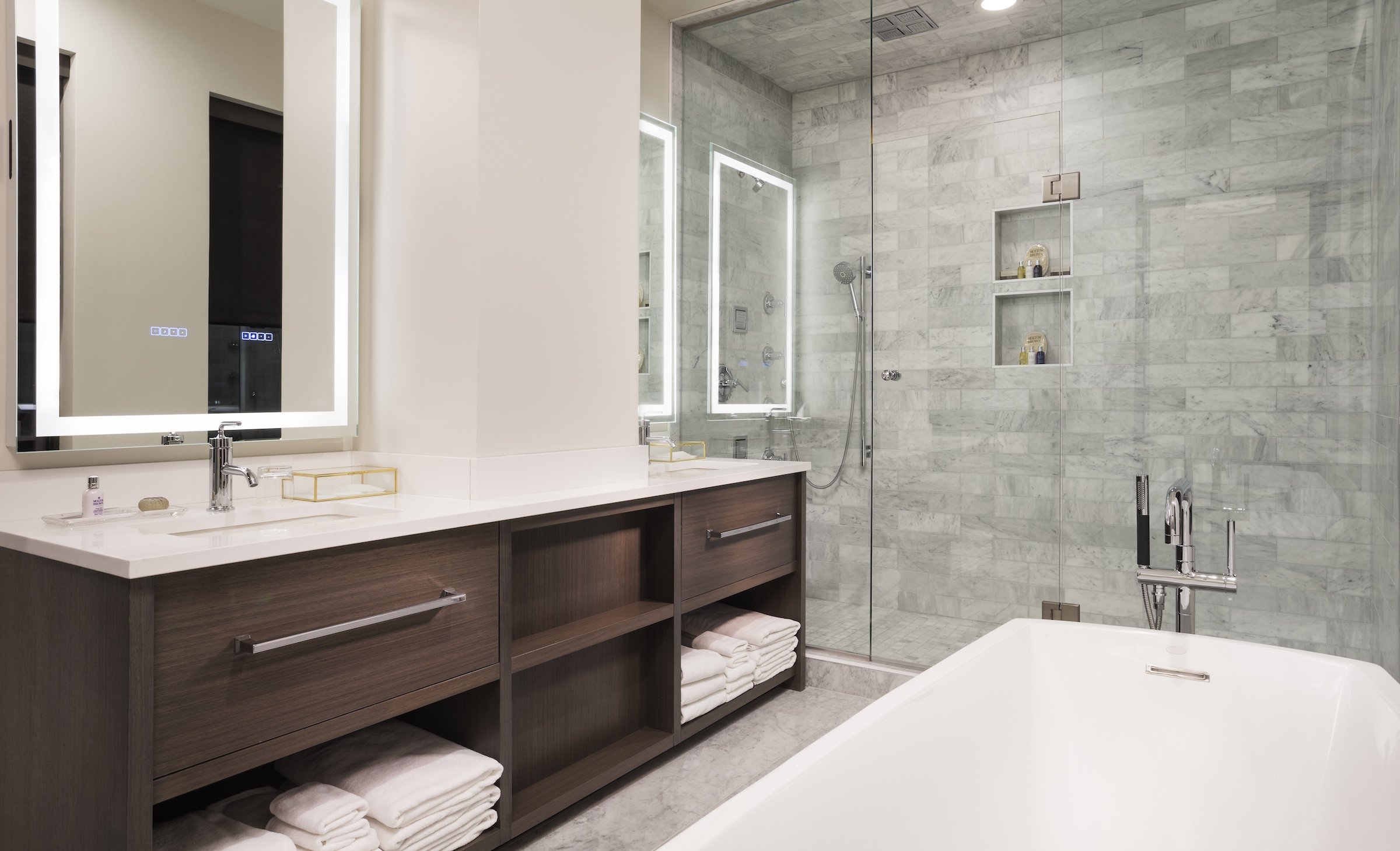 A sink filled with towels and amenities, shower booth, and a white bath tub at Penthouse Suite of Hotel Ivy