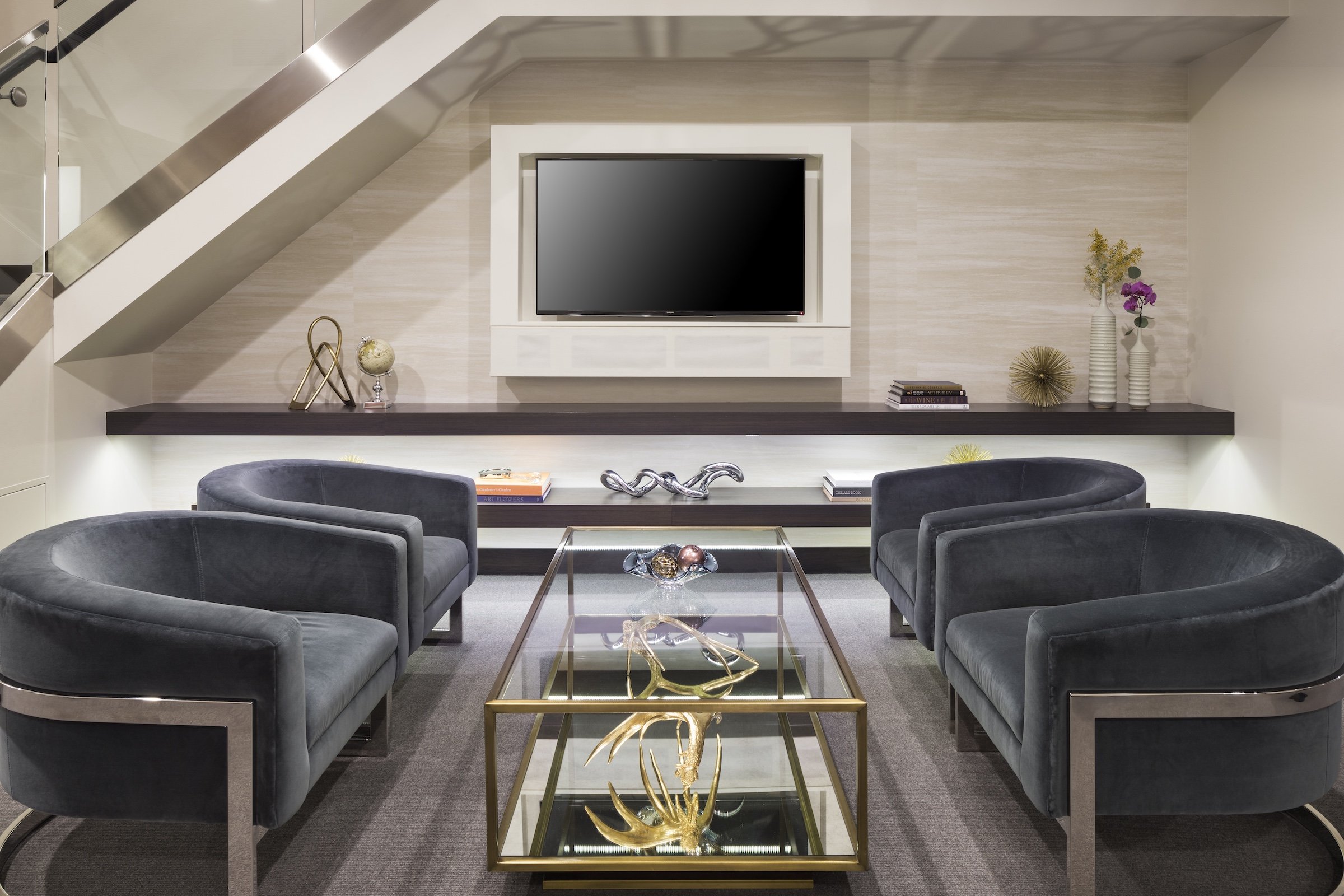 A classic modern interior of a living room that has four arm chairs, a large glass tea table, Cable TV, and some decorations at Penthouse Suite of Hotel Ivy