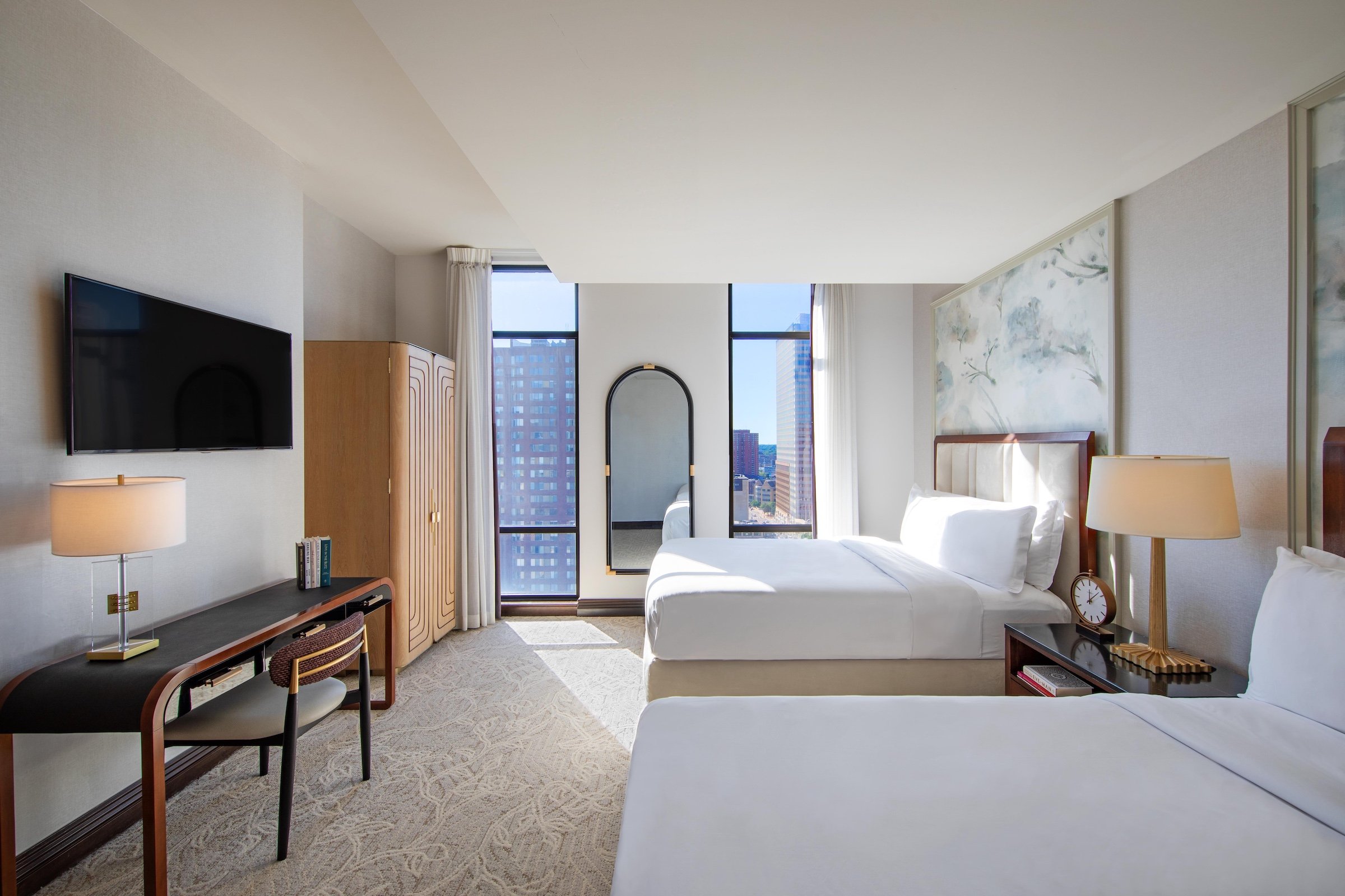 A large modern room with two king beds, desks, and cable tv next to large windows at Hotel Ivy