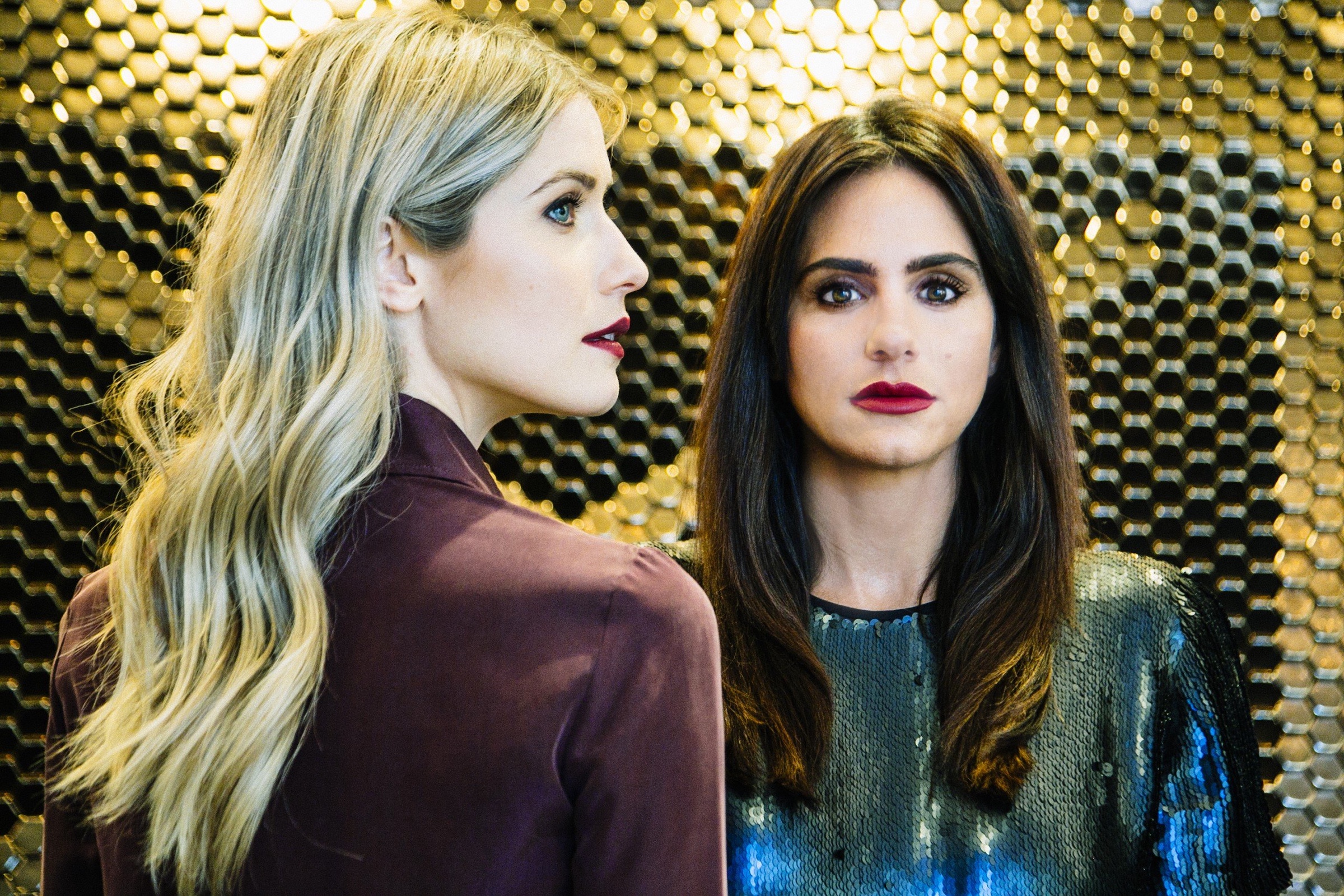 A woman with brown hair looking at the camera and the other women with blond hair looking at the side at Hotel Ivy